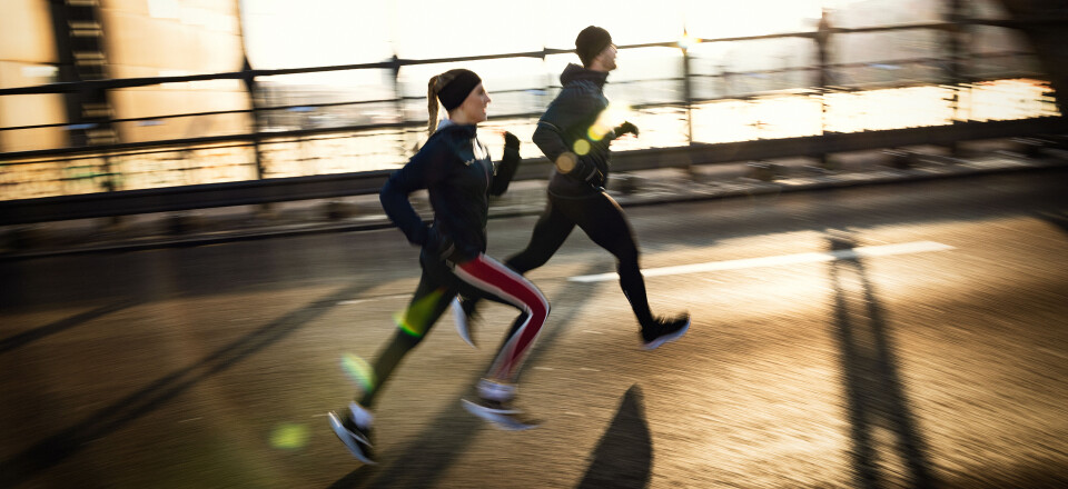 Ein Mann und eine Frau laufen bei Sonnenaufgang auf einer sonnigen Brücke in Sportkleidung für ein Outdoor-Fitnesstraining.
