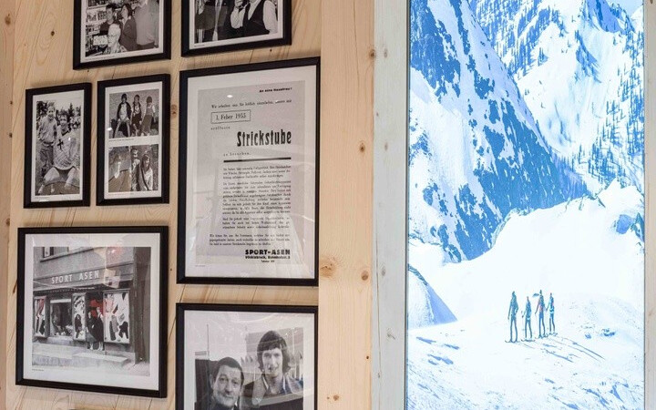 Holzwand mit einer Schwarz-Weiß-Fotogalerie und einem großen Bildschirm, der verschneite Berge anzeigt.