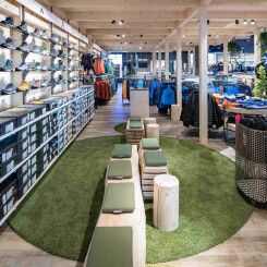 Heller Verkaufsraum mit Holzdecken, der Outdoor-Schuhe, Bekleidung und einen Schuh-Anprobierbereich präsentiert.