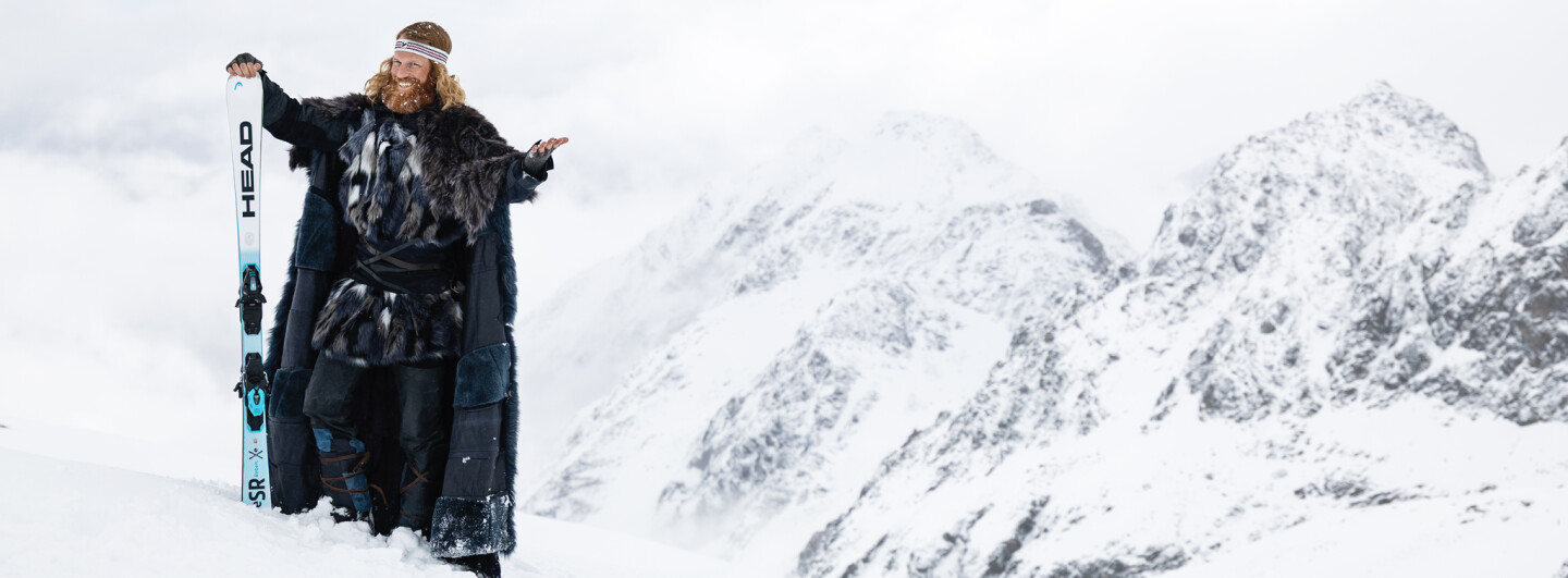 Herr Winter mit Ski am verschneiten Berg
