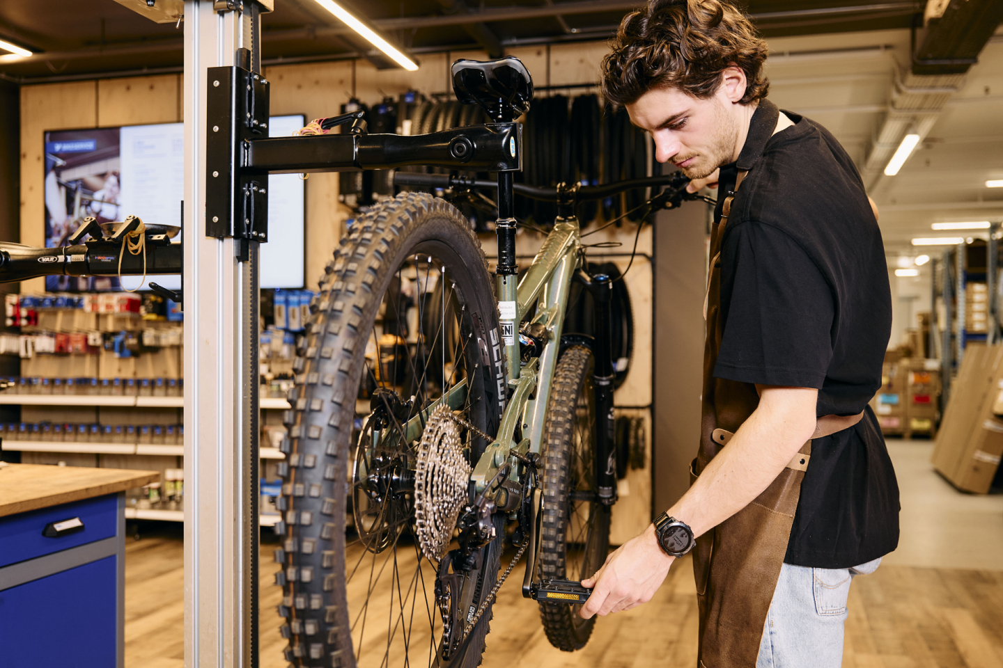 Ein Fahrradmechaniker wartet ein Mountainbike auf einem Montageständer in einem professionellen Fahrradgeschäft.