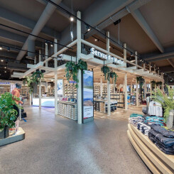 Gut beleuchtetes, modernes Ladeninterieur mit Bekleidung, Outdoor-Bekleidung, Schaufensterpuppen und hölzernen Präsentationsmöbeln.