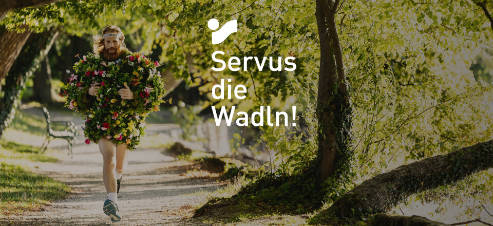 Mann in einem grünen Blätter- und Blumenanzug läuft auf einem schattigen Parkweg und wirbt für Outdoor-Fitness.